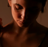 Close-up portrait of a woman in warm low-key lighting with her eyes downcast