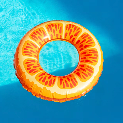 Orange citrus-slice pool float drifting on bright blue swimming pool water