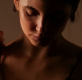 Close-up portrait of a woman in warm low-key lighting with her eyes downcast